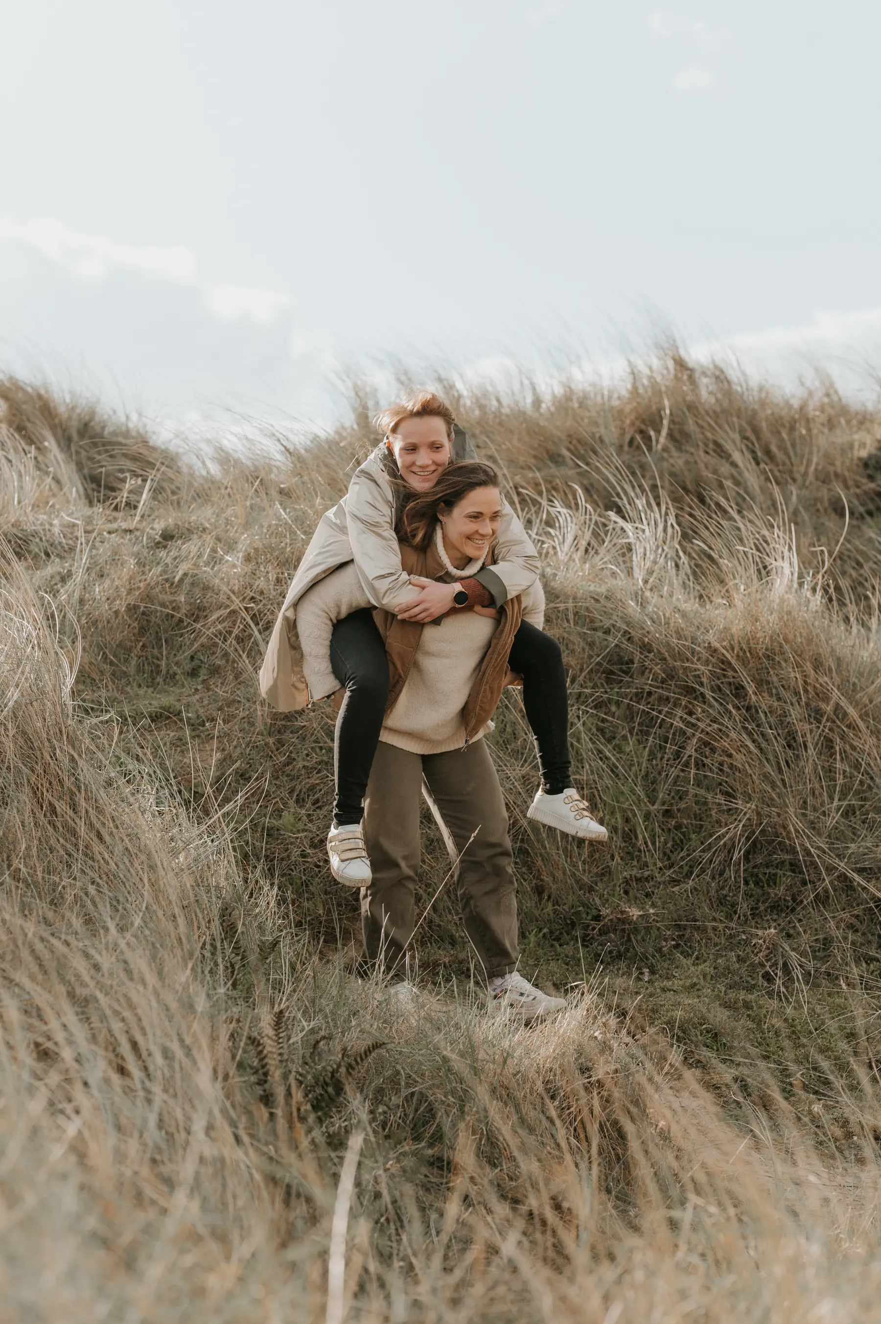 Une mère porte sa fille au sommet d’une dune.