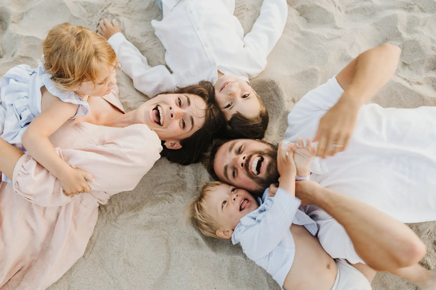 Une famille forme une ronde sur le sable.