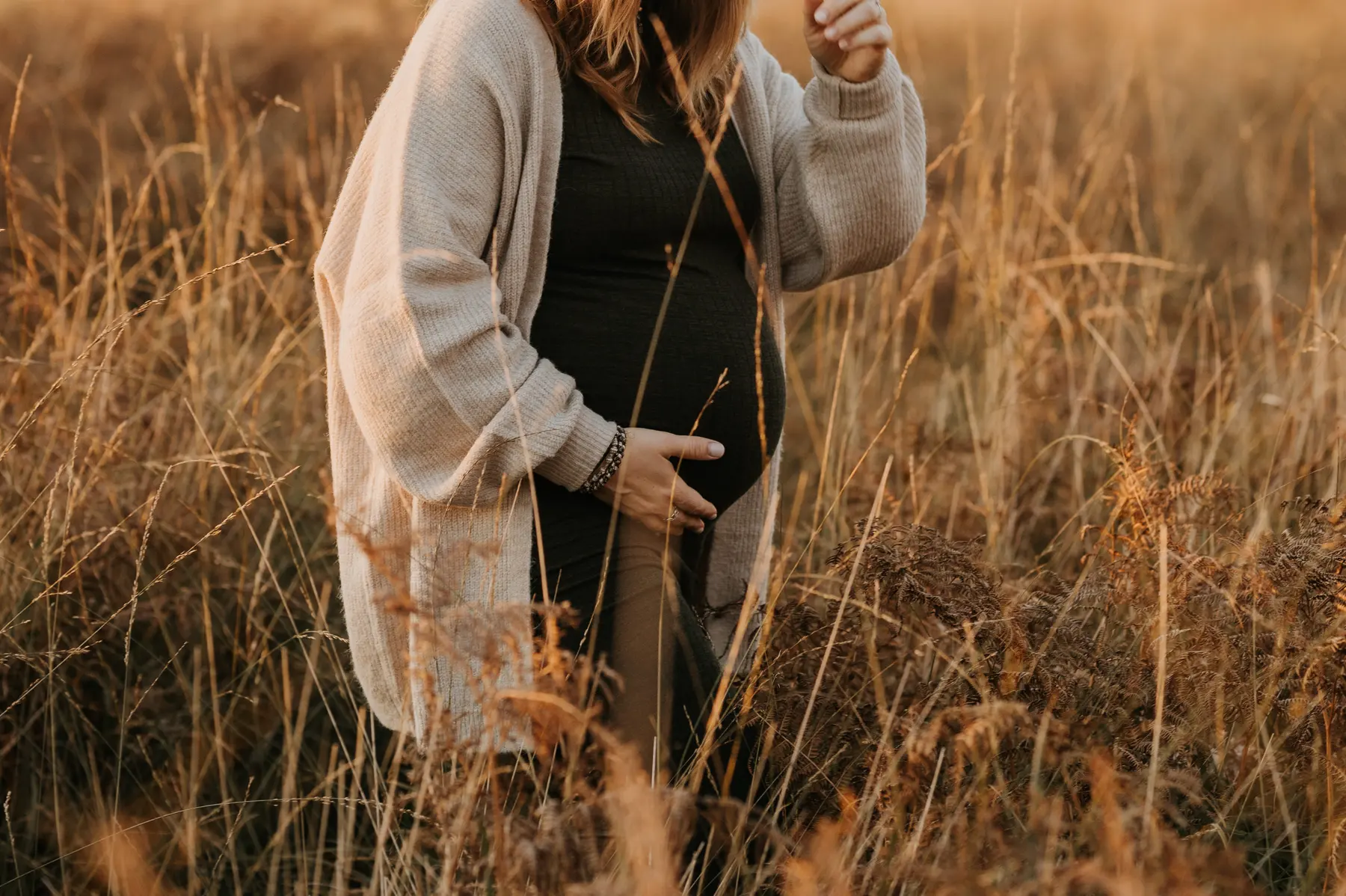 Une femme enceinte marche dans un champ doré.