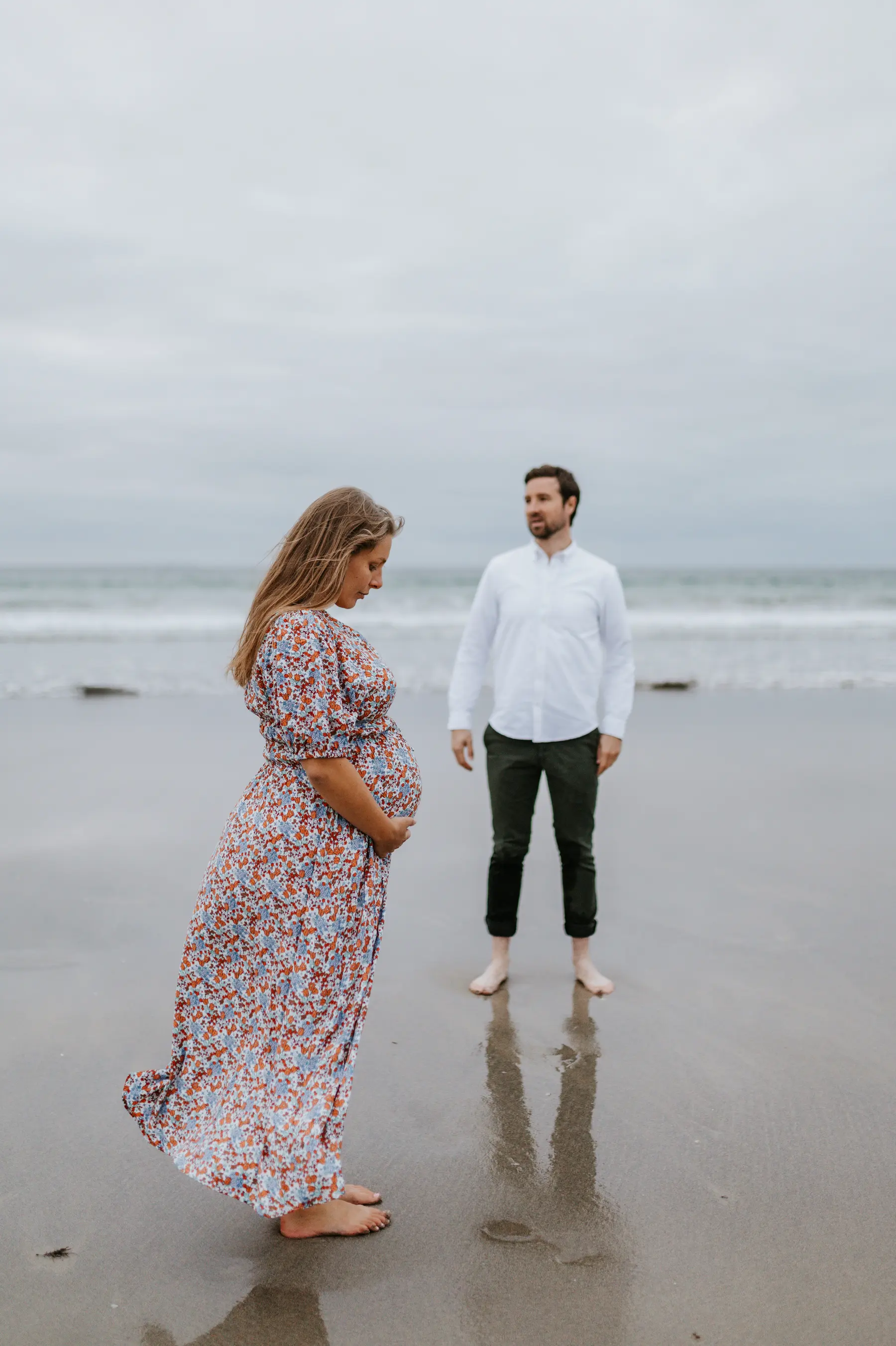 Un couple se reflète dans le sable mouillé.