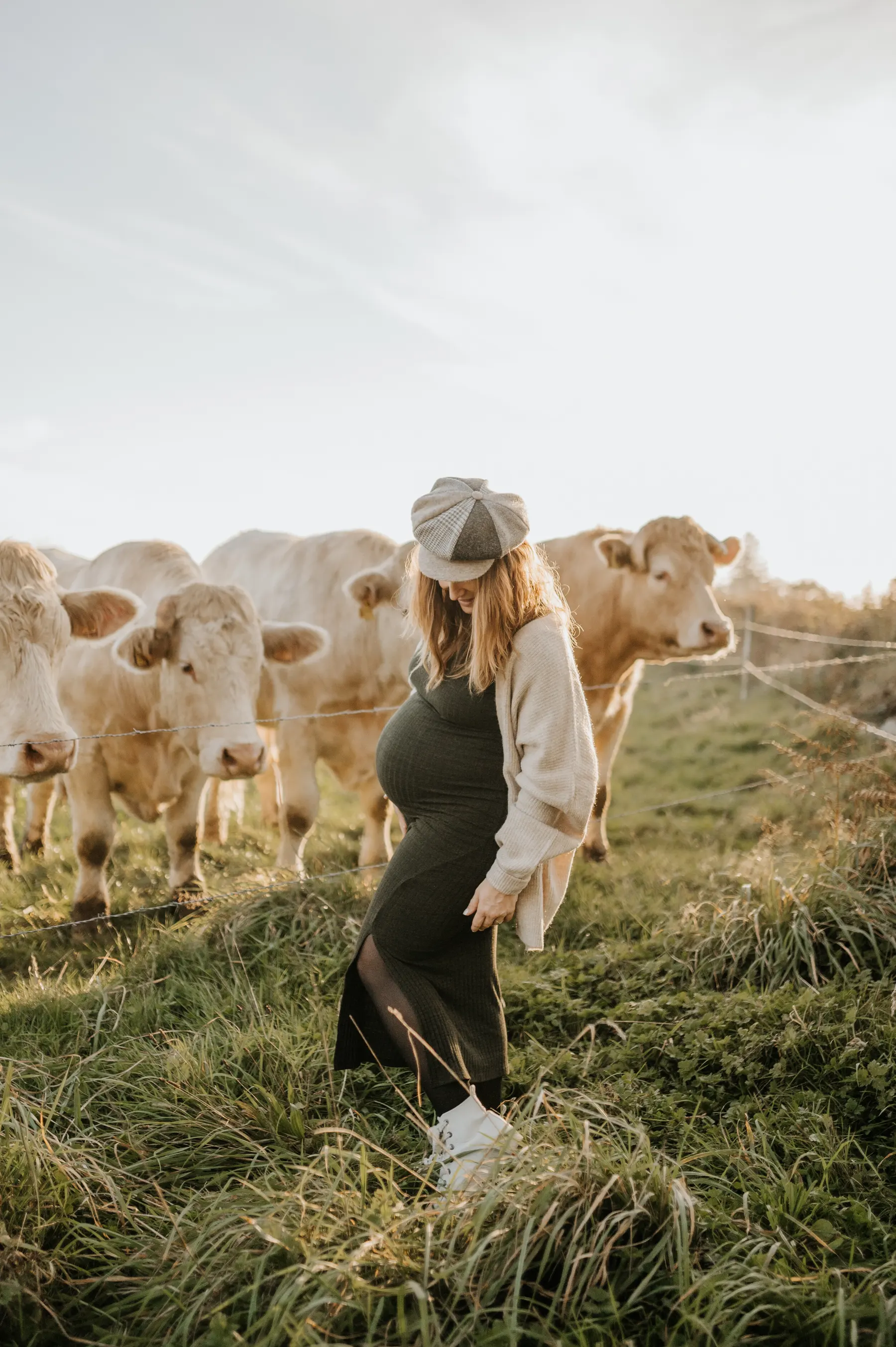 Une femme enceinte dans un pré, entourée de vaches.