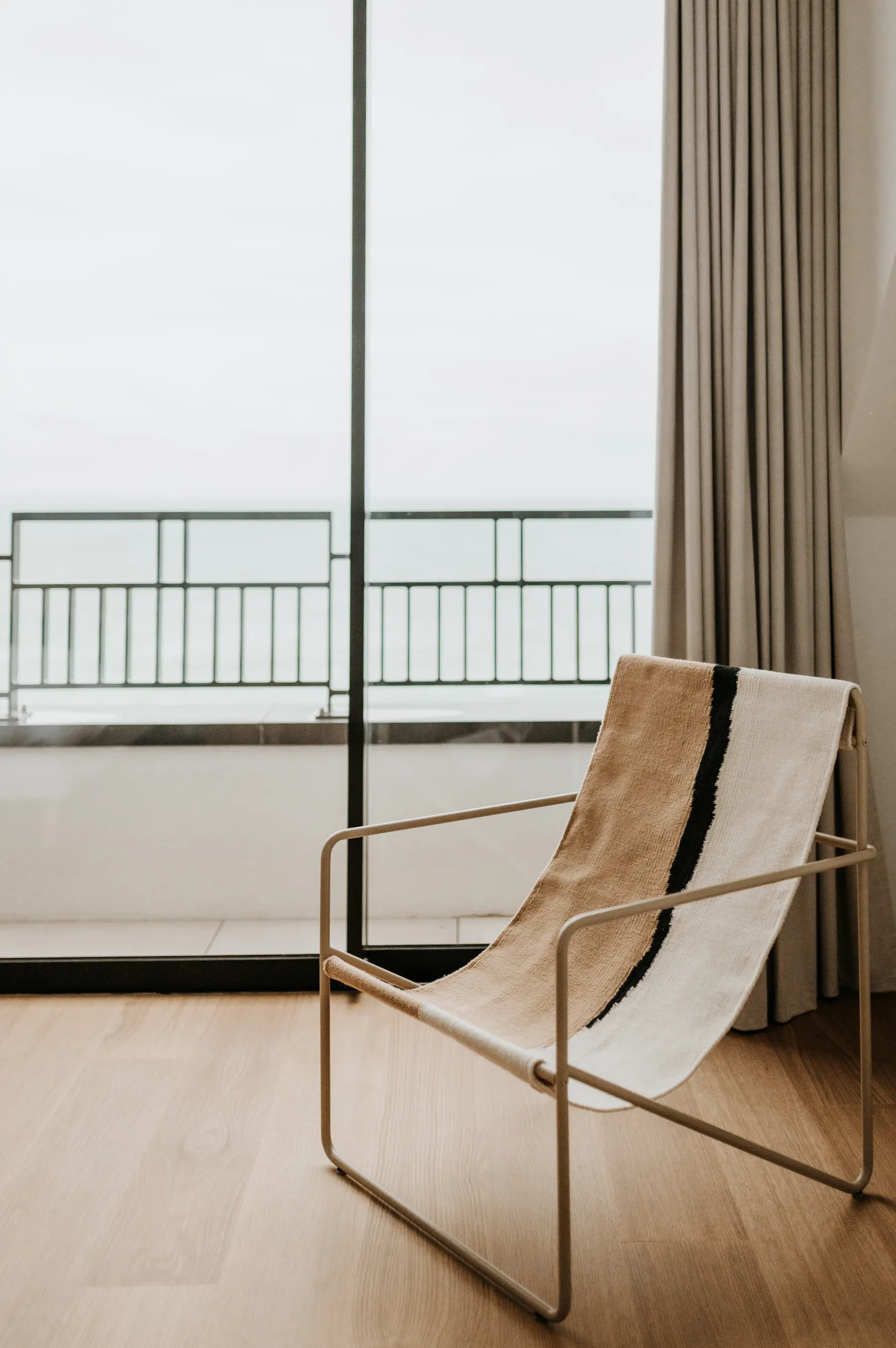 Une chaise longue installée devant une baie vitrée.
