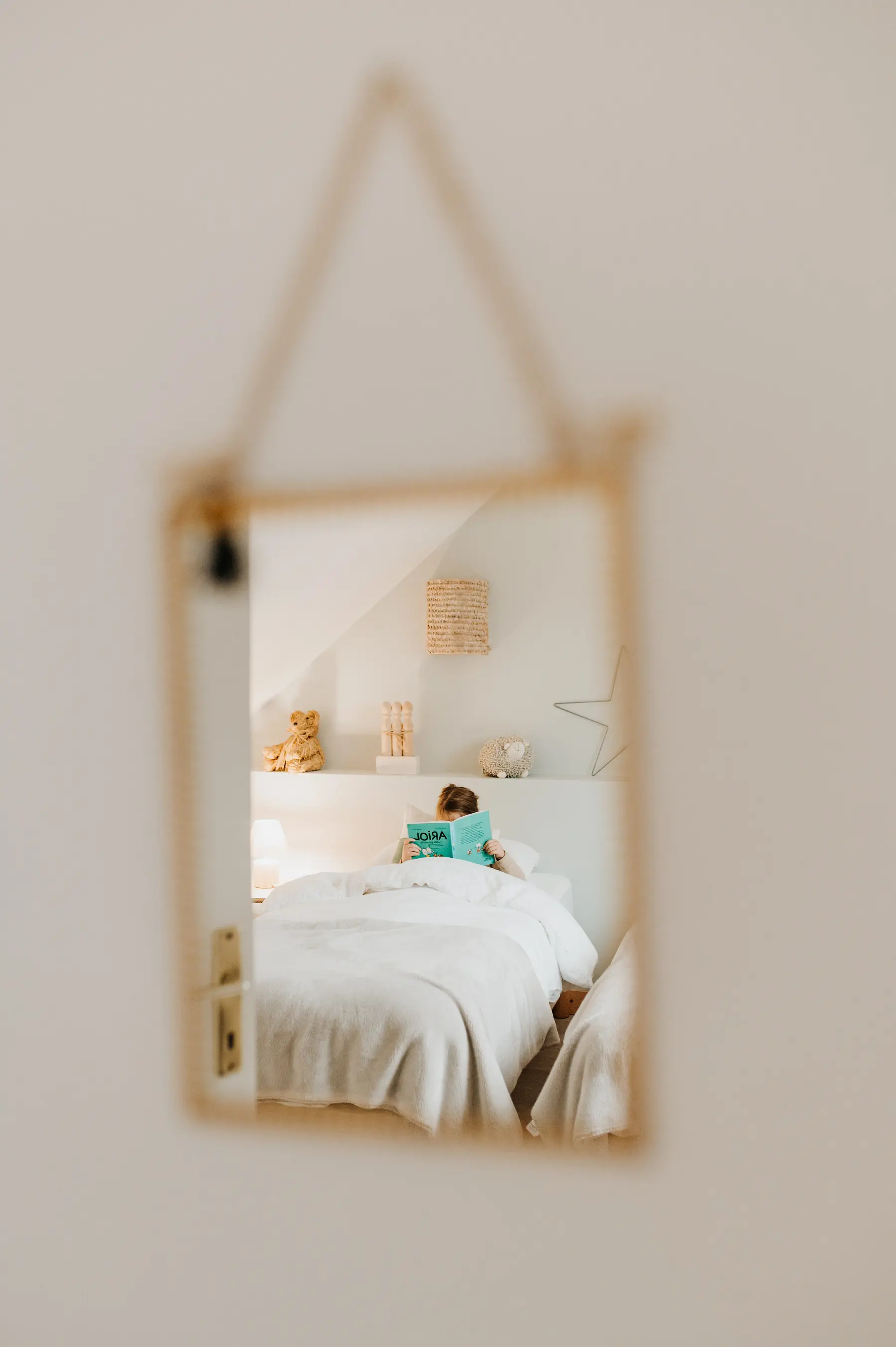 Un miroir reflète un lit et un enfant qui joue.