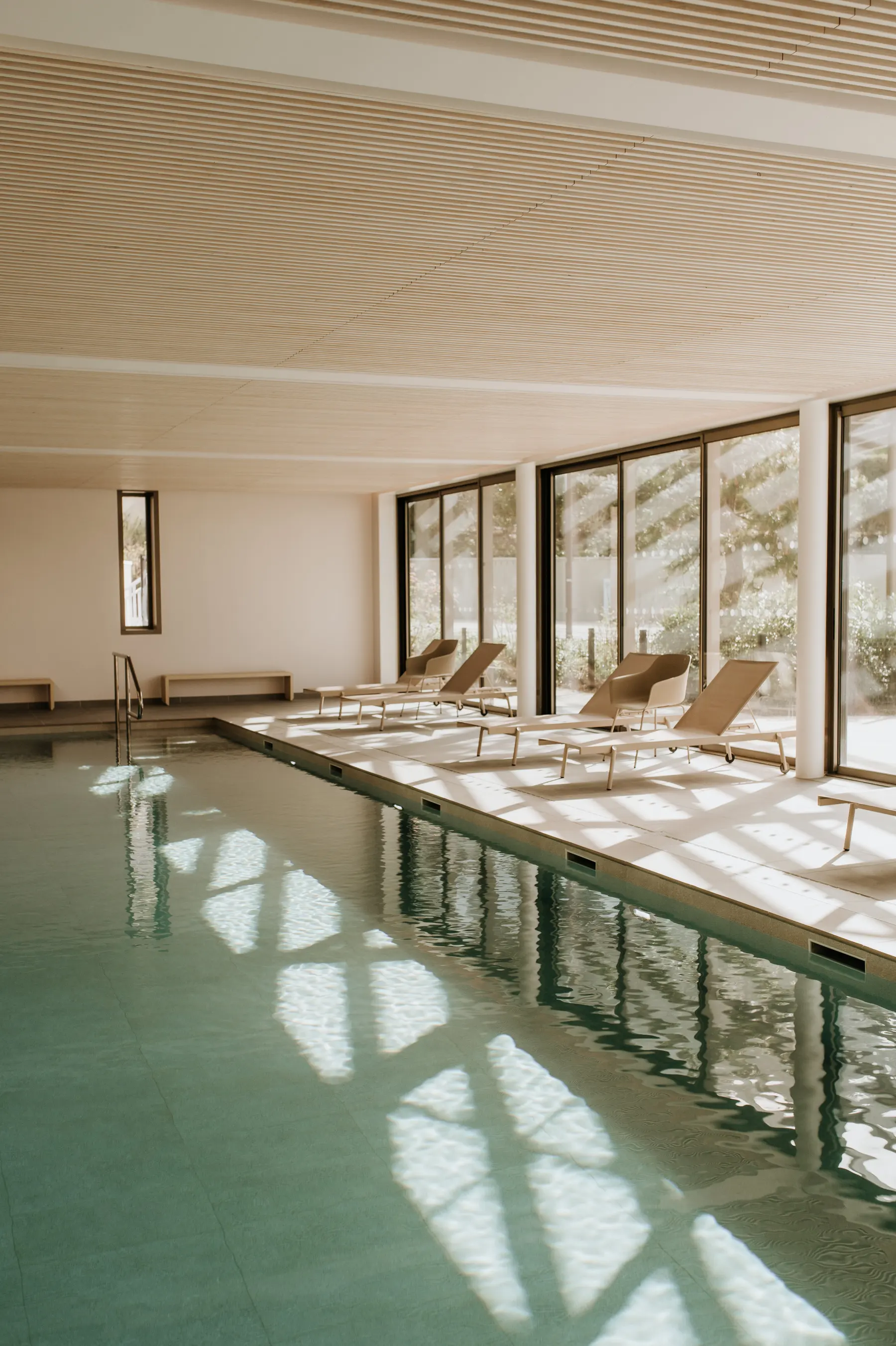 Une piscine intérieure couverte, bordée de transats.