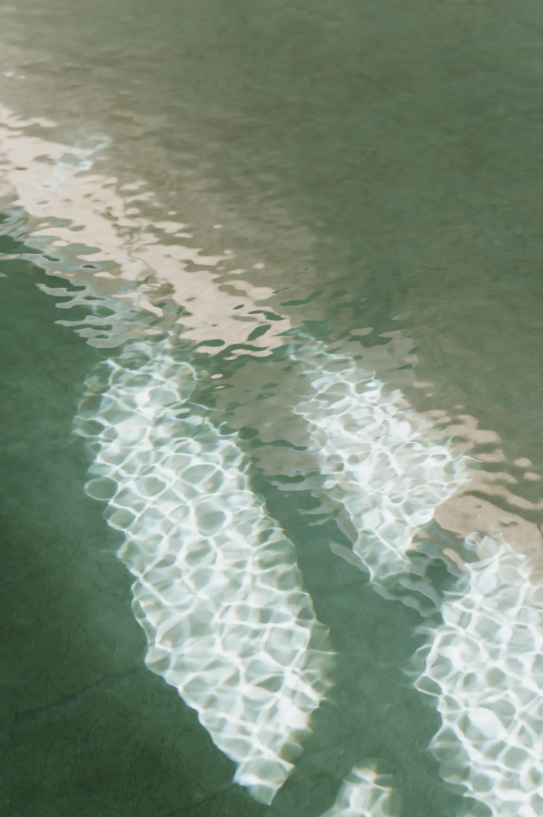 Des reflets de lumière ondulent sur l’eau d’une piscine.