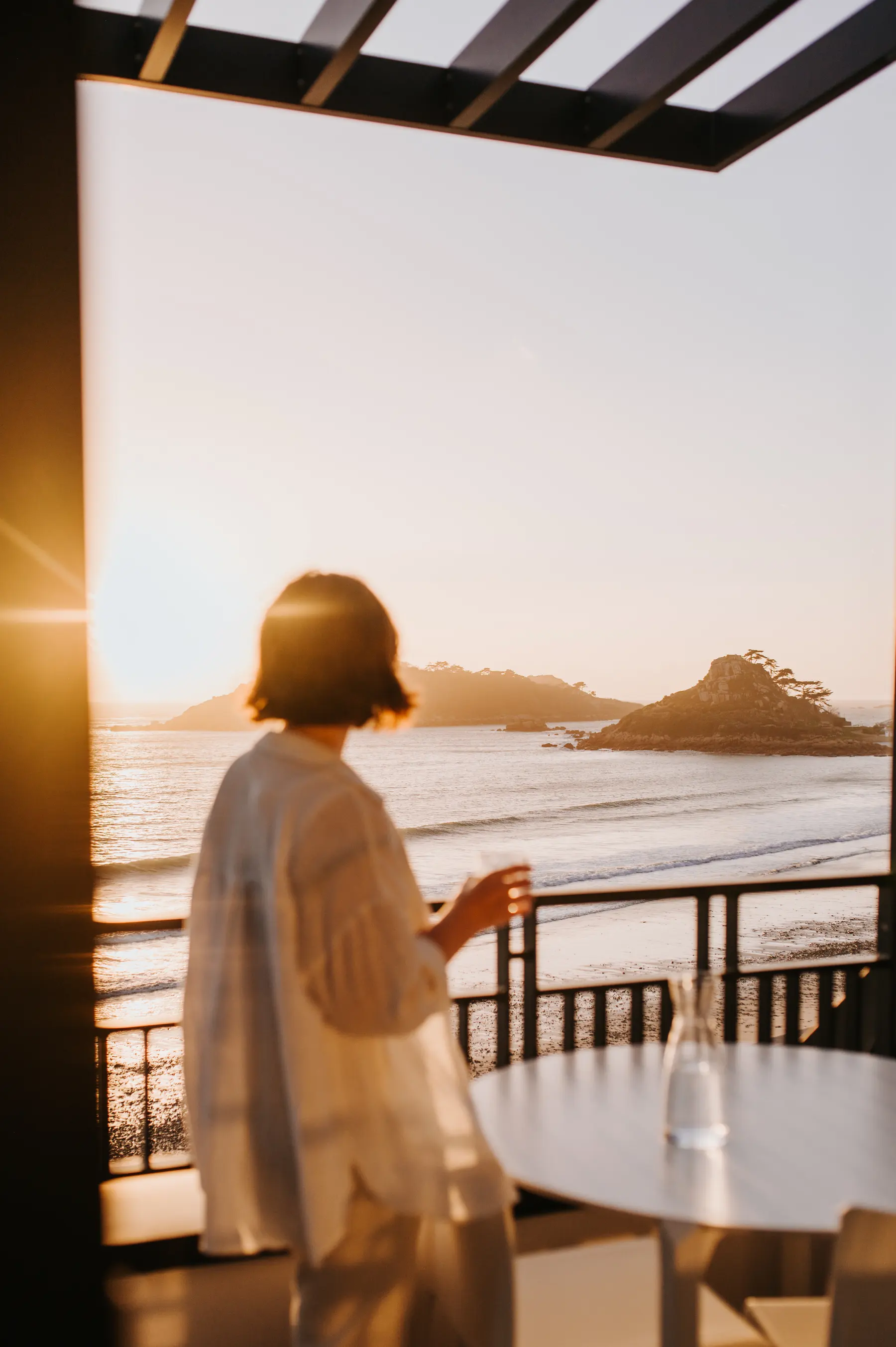 Une femme regarde la mer depuis une terrasse.