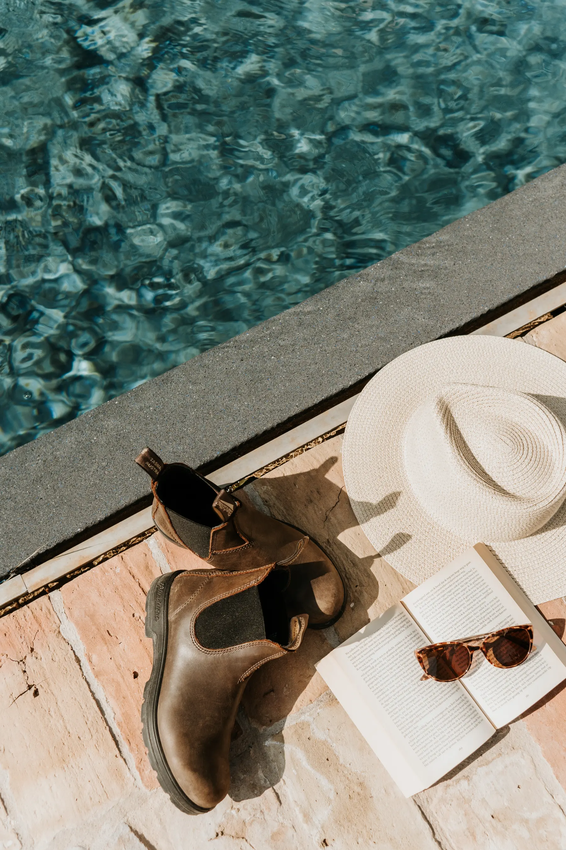 Des bottines et un chapeau au bord d’une piscine.