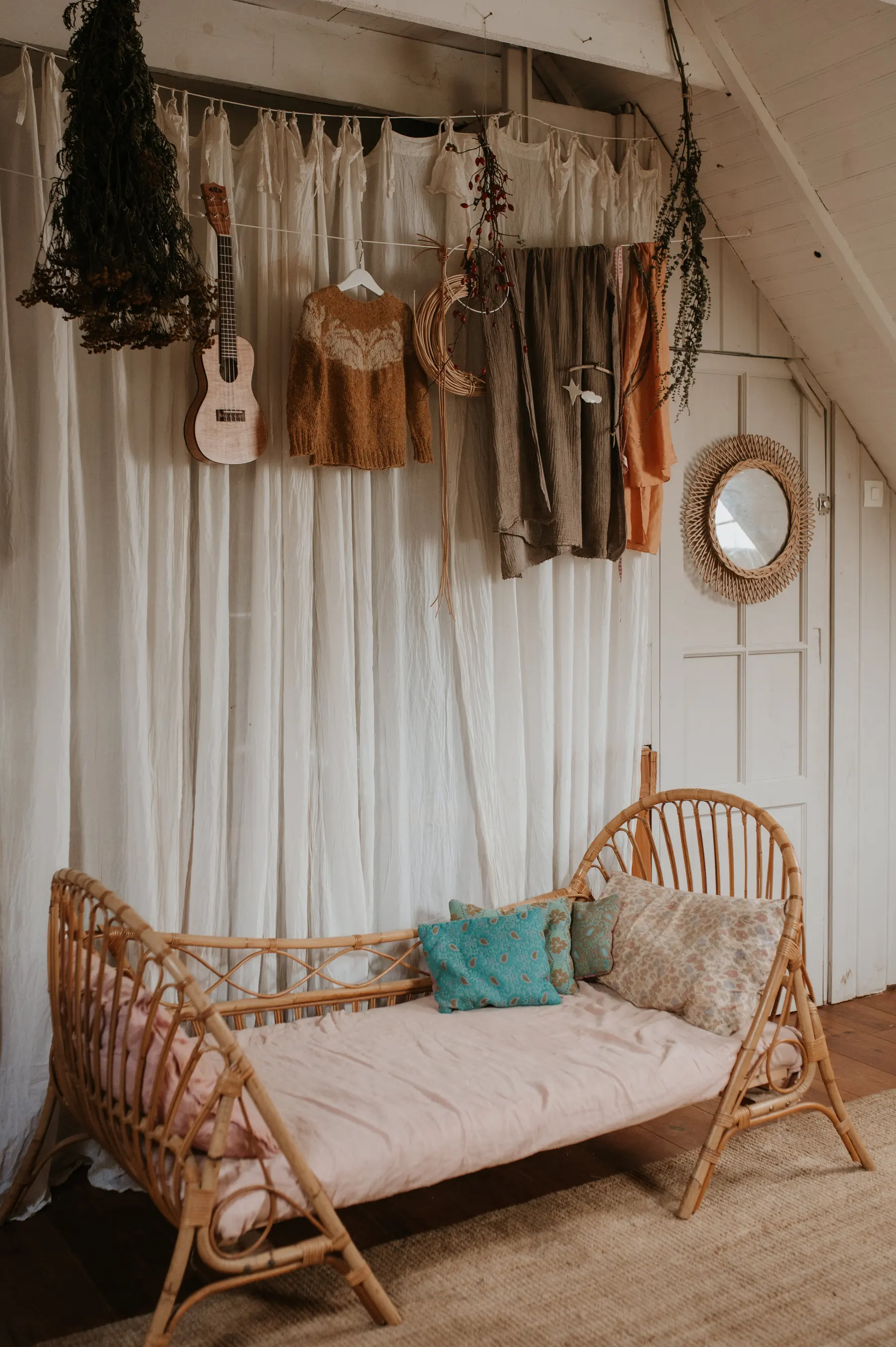 Une chambre d’enfant, lit de rotin et ukulélé posé au mur.