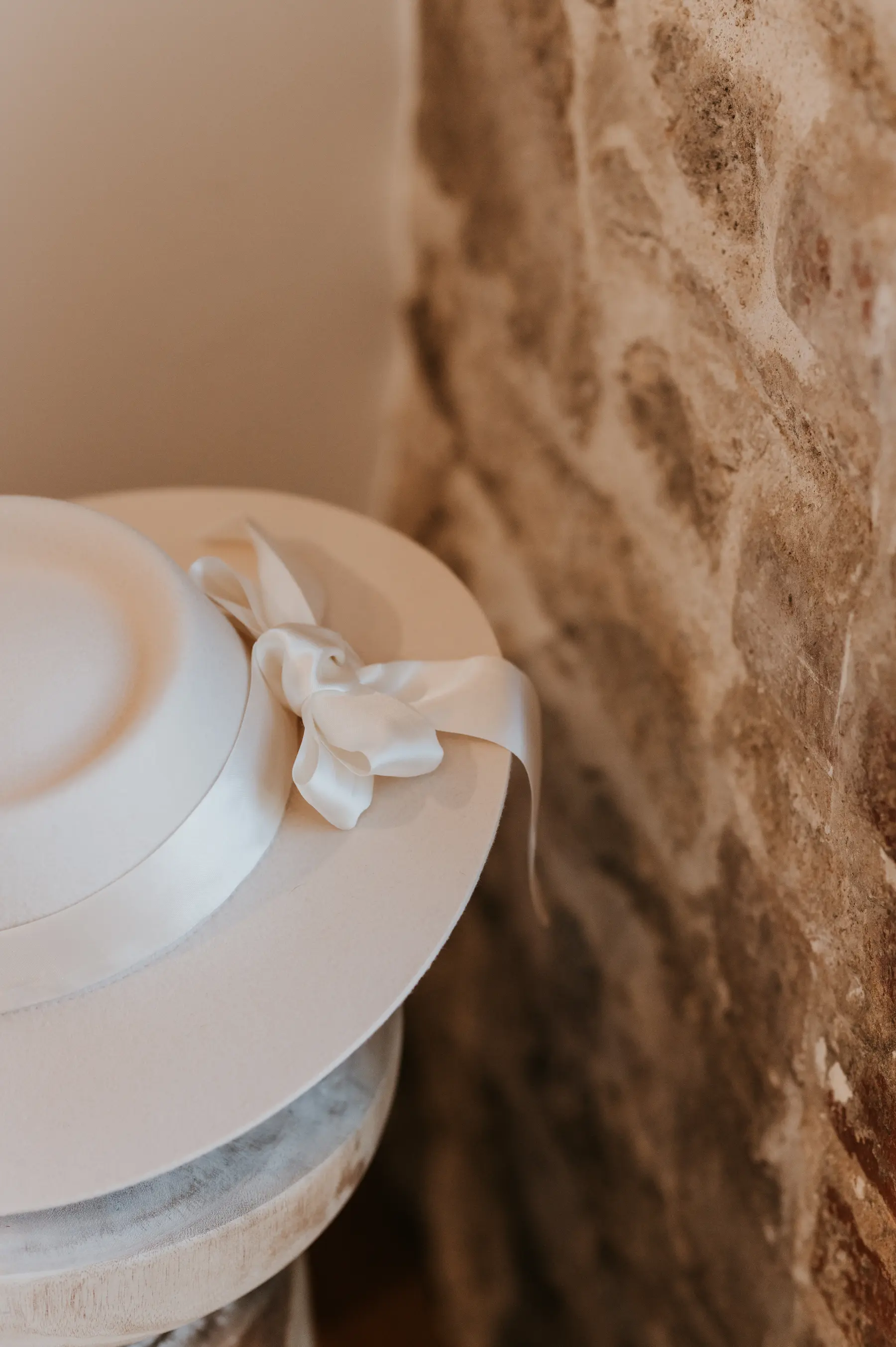 Un chapeau blanc accroché à un mur de pierre.