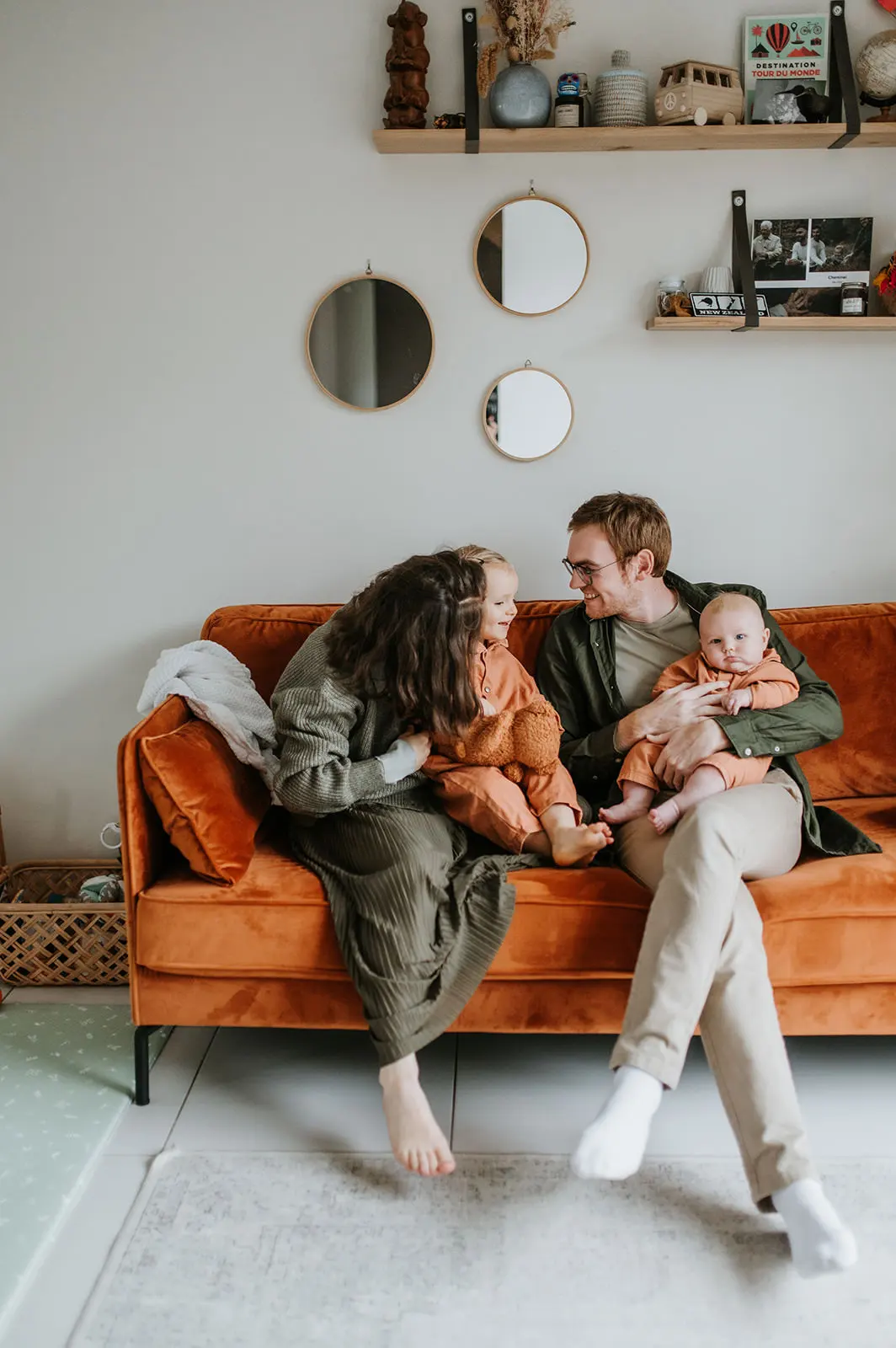 Une famille réunie sur un canapé orange, au salon.