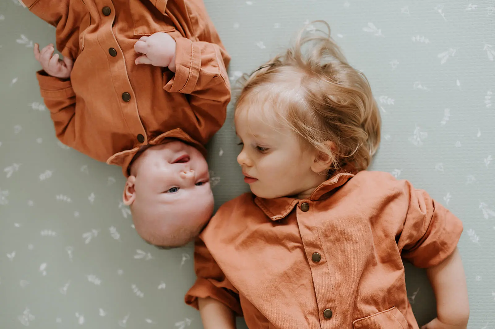 Deux bébés en tenue orange, photographiés de haut.