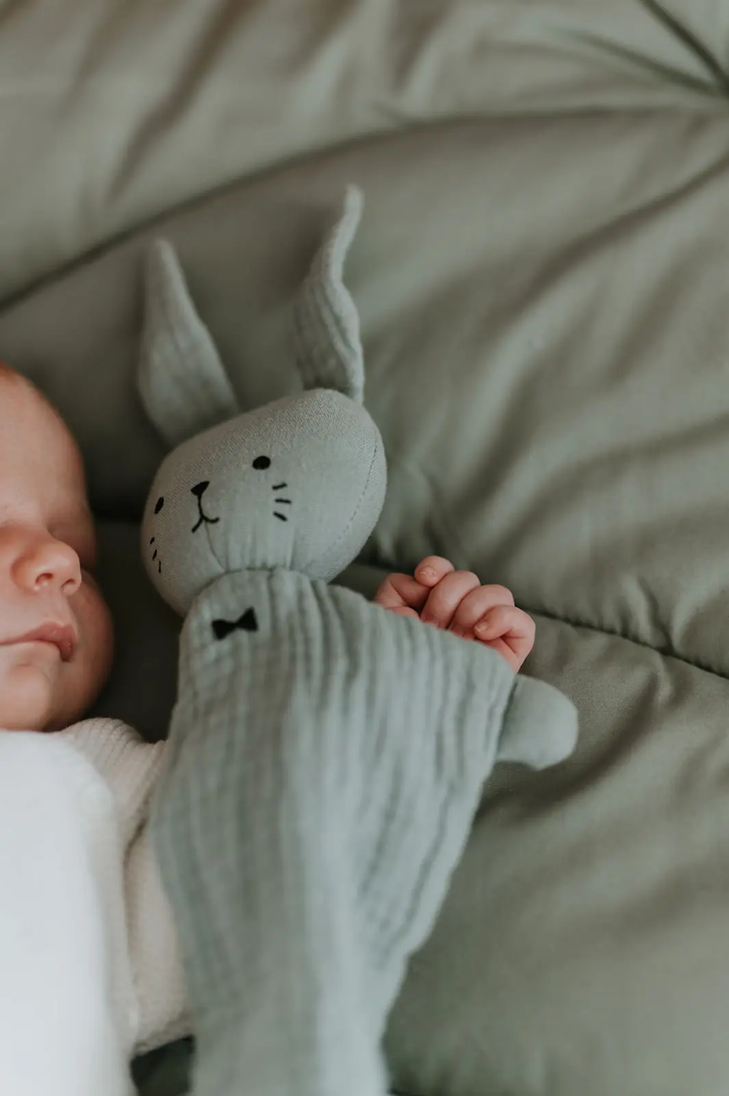 Un nouveau-né endormi contre son doudou lapin.