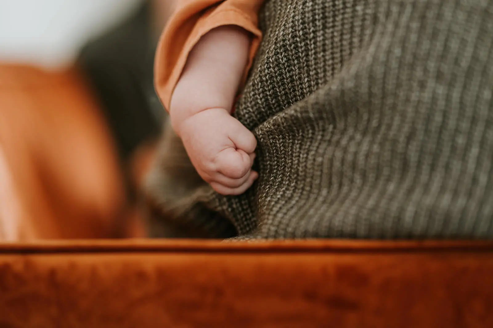 La main d’un bébé posée sur l’épaule d’un parent.
