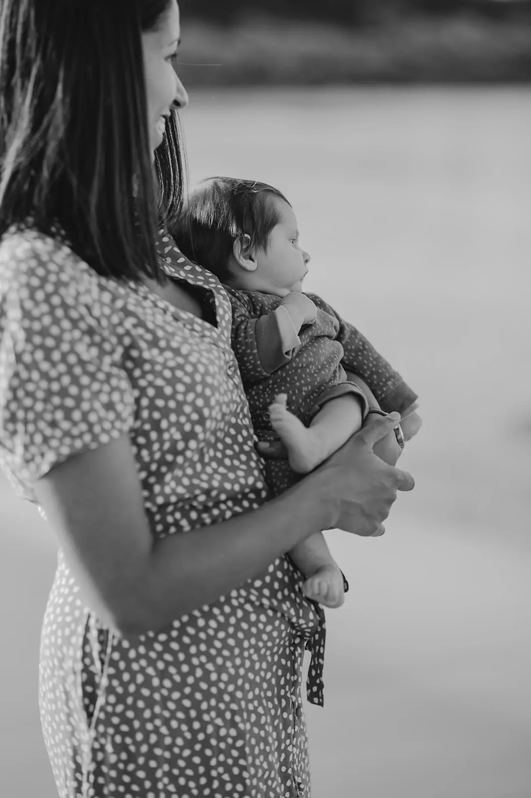 Une mère porte son bébé, en noir et blanc.