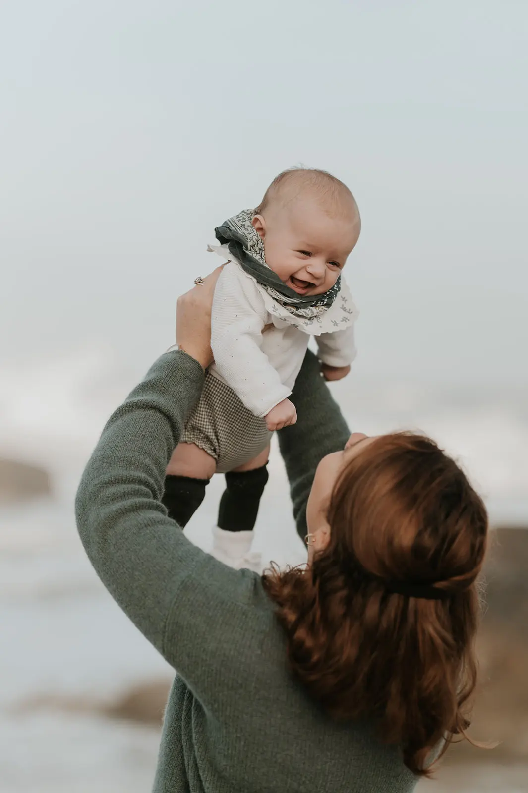 Un père soulève son bébé au soleil couchant.