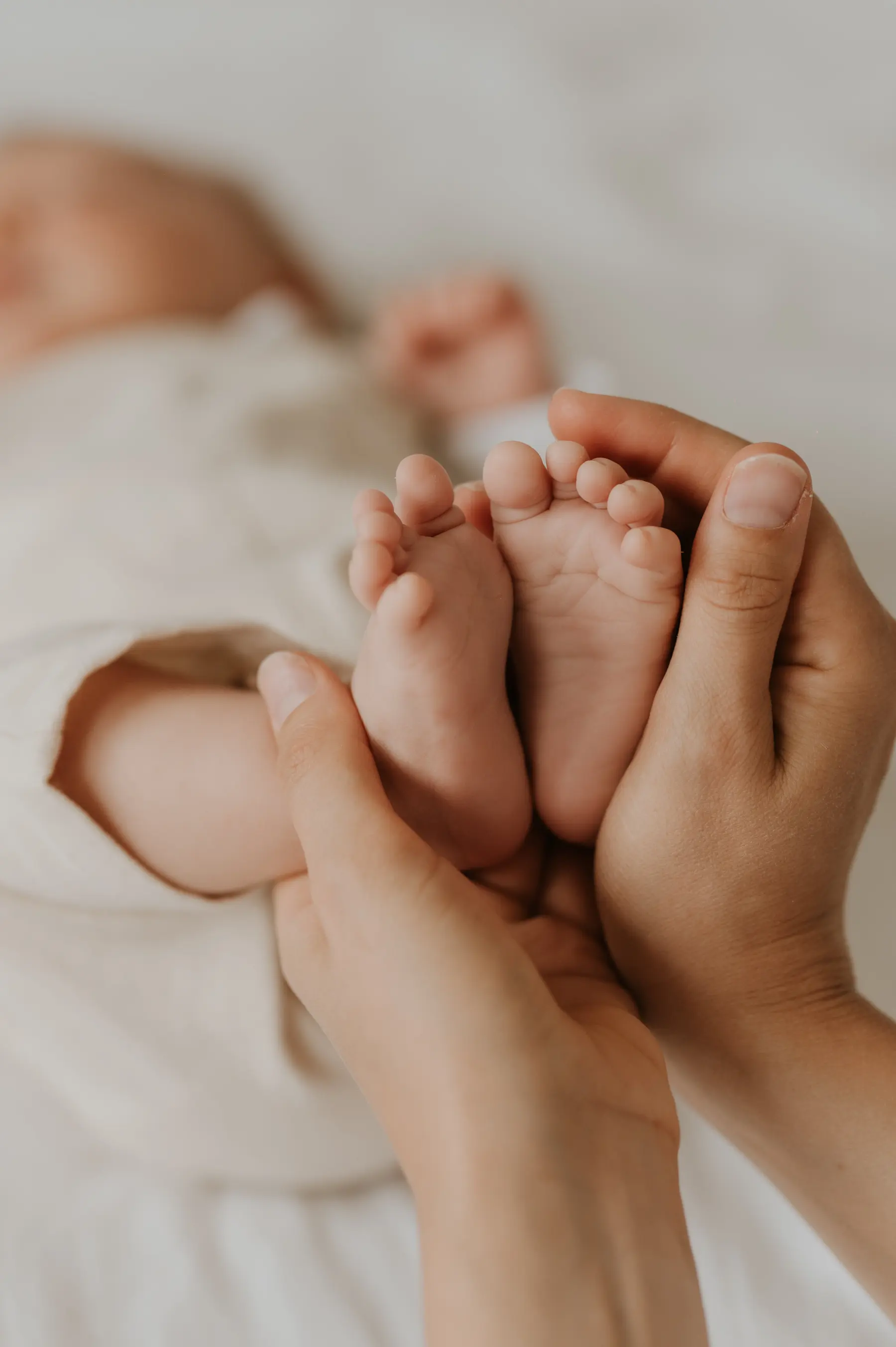 Les pieds d’un bébé posés dans les mains de ses parents.