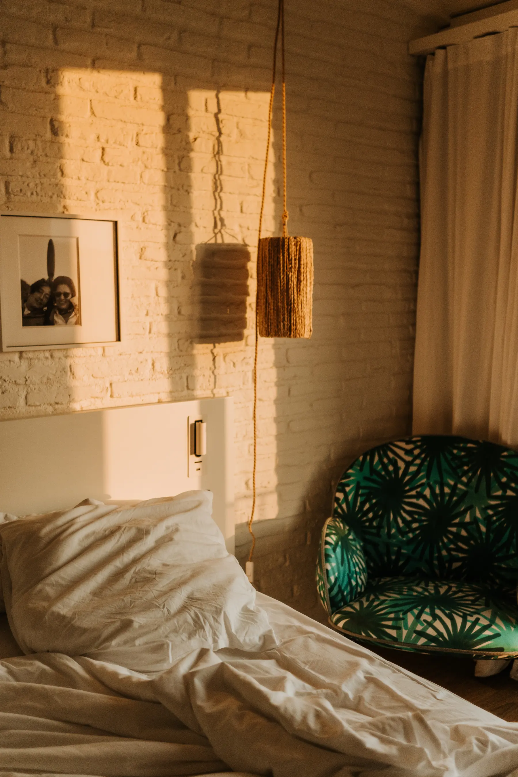 Une chambre au lit défait, adossée à un mur de briques apparentes.