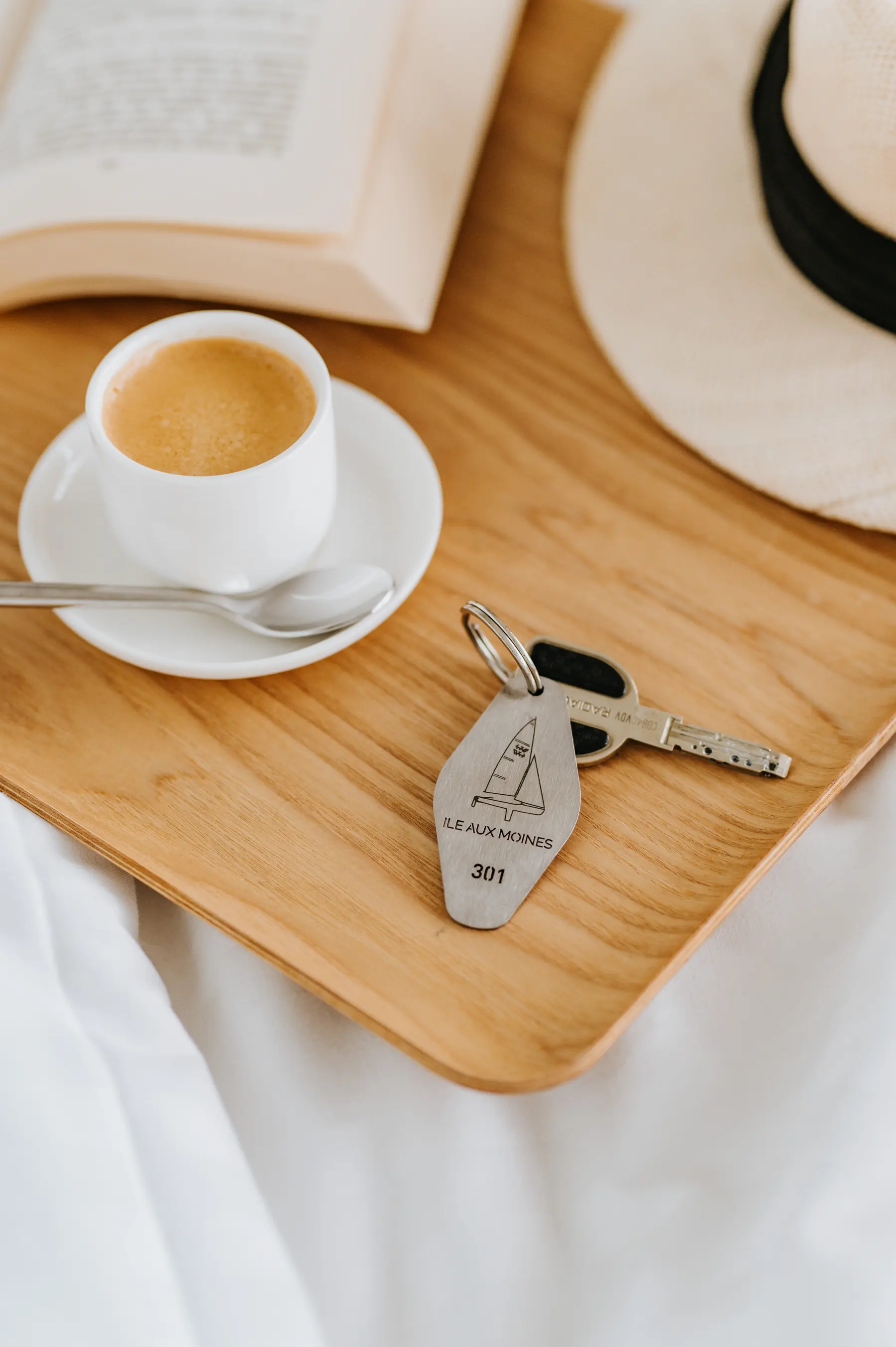 Un plateau de café, un chapeau de paille et un trousseau de clés posés sur un lit.