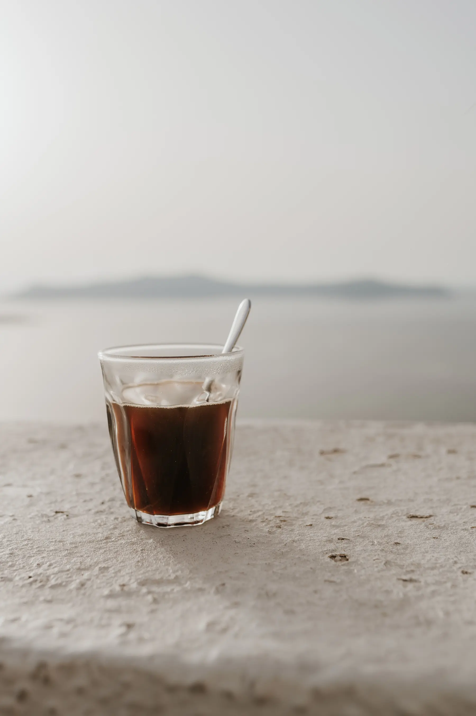 Un verre de café glacé posé face à la plage.