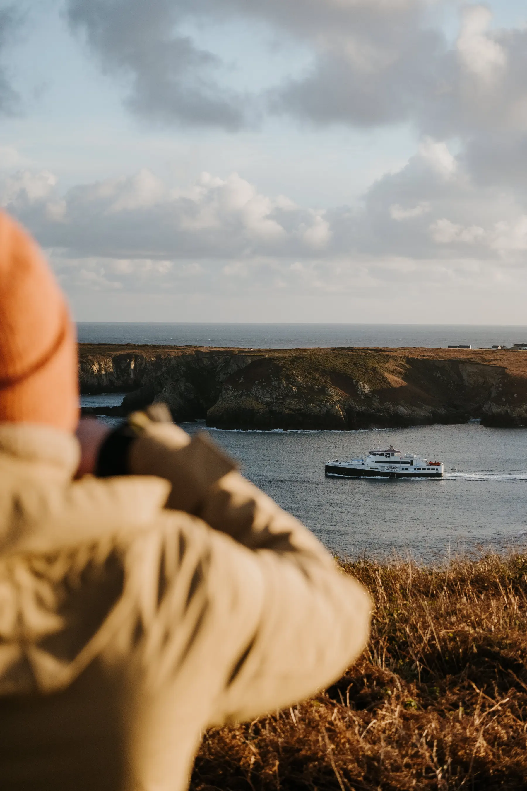 Une femme photographie une baie depuis le rivage.