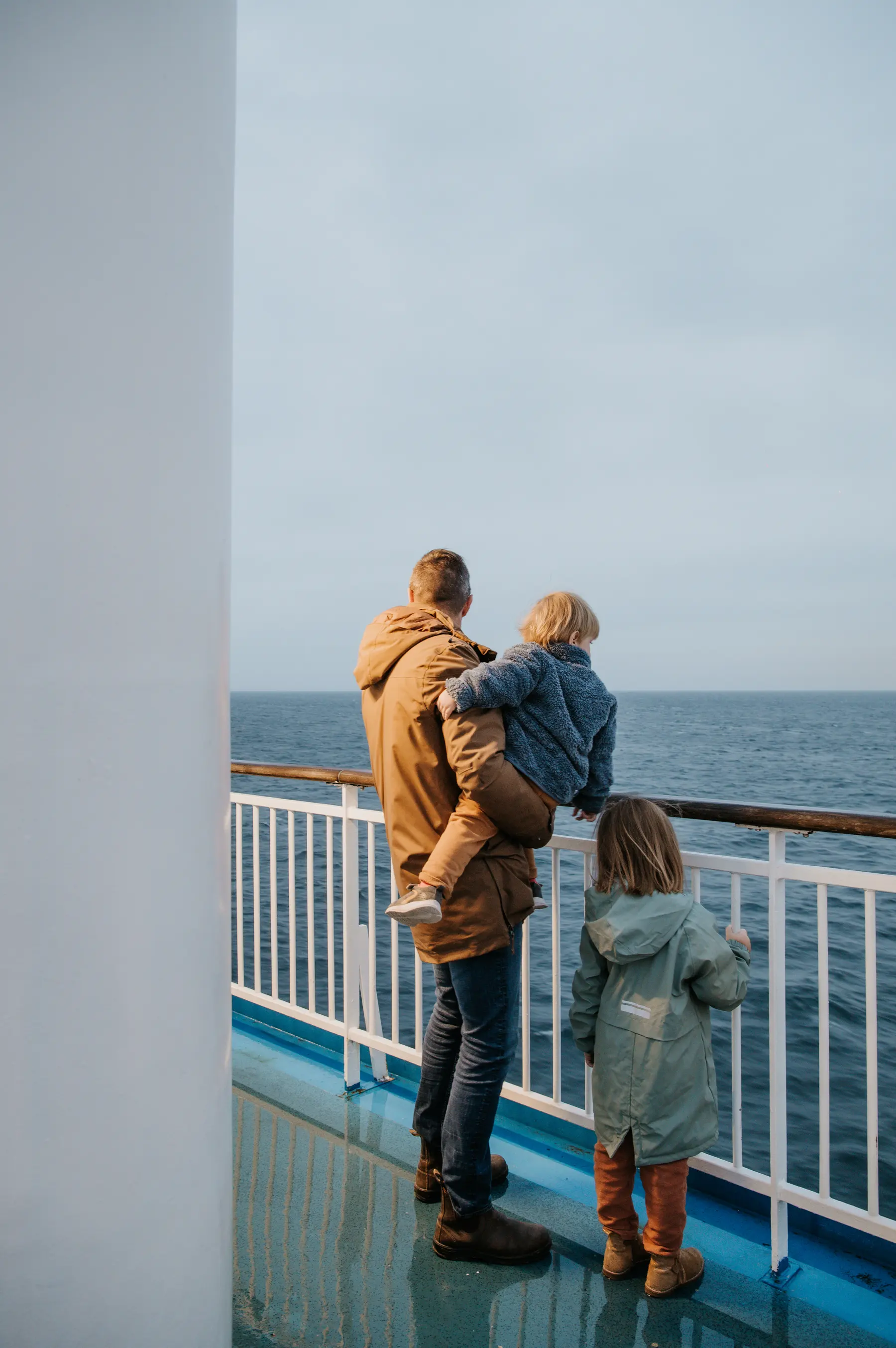 Un père et ses enfants sur le pont d’un ferry.
