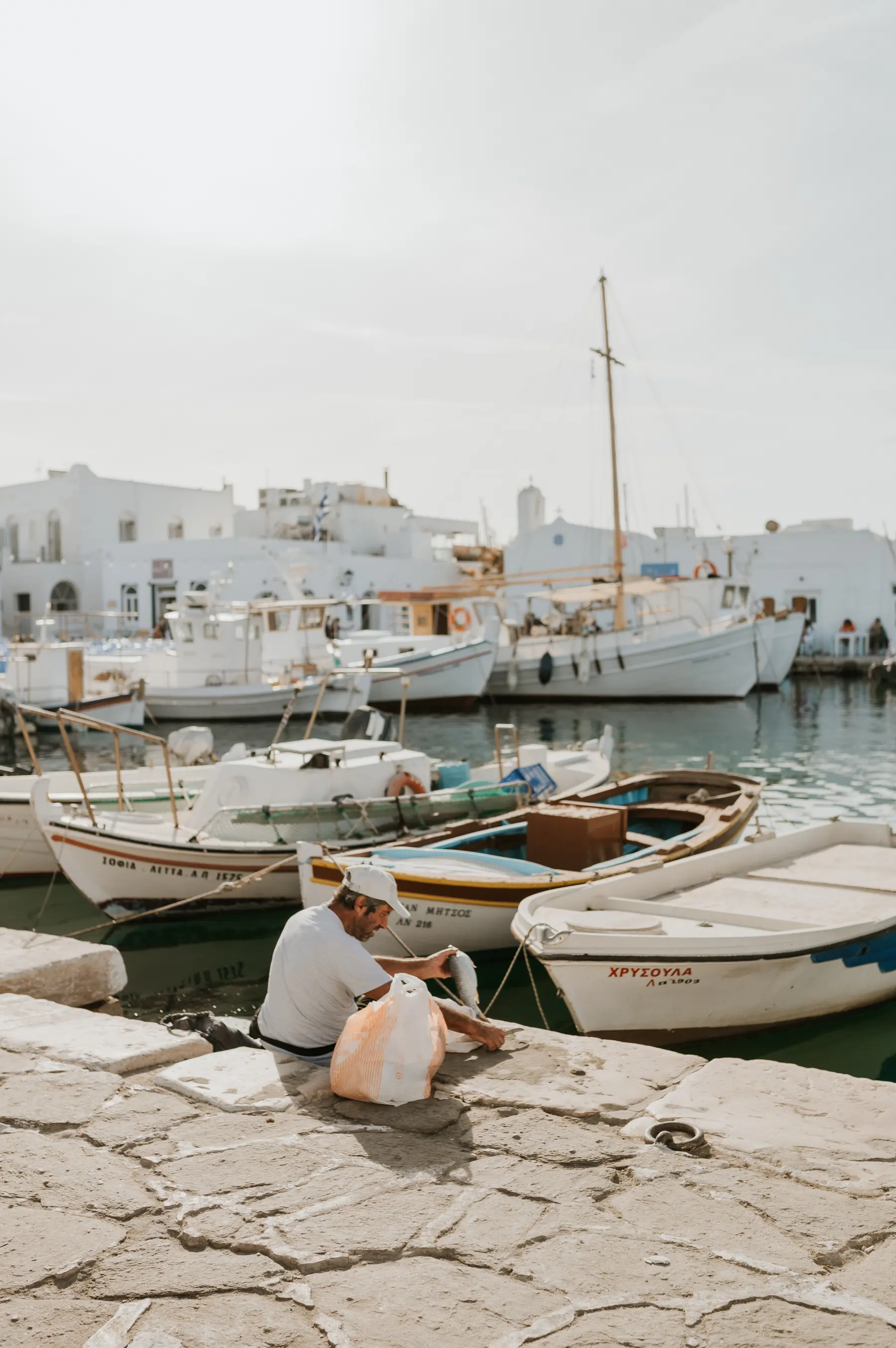 Les bateaux d’un port devant un village blanc.